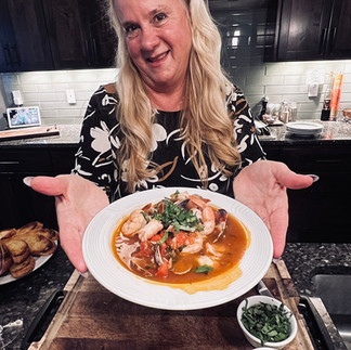 Treva showing plated cioppino with basil garnish