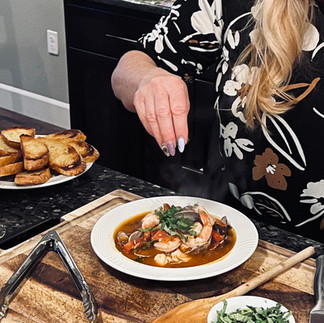 Treva adding basil garnish to cioppino