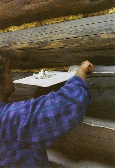 Applying the mortar chinking to the spaces between the logs