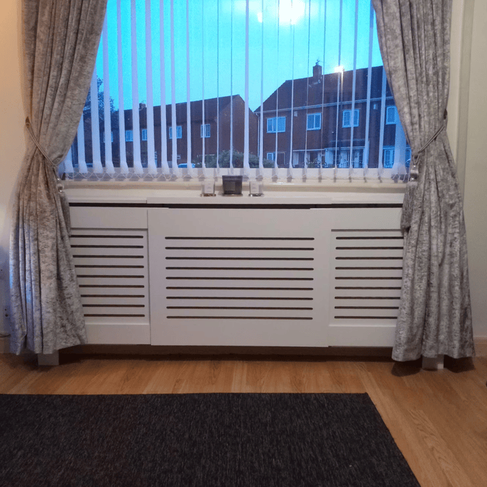 A white radiator with minimal decor on top shelf in a living room hallway.