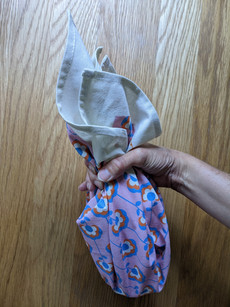 Hand wrapped around neck of glass bottle holding fabric in place