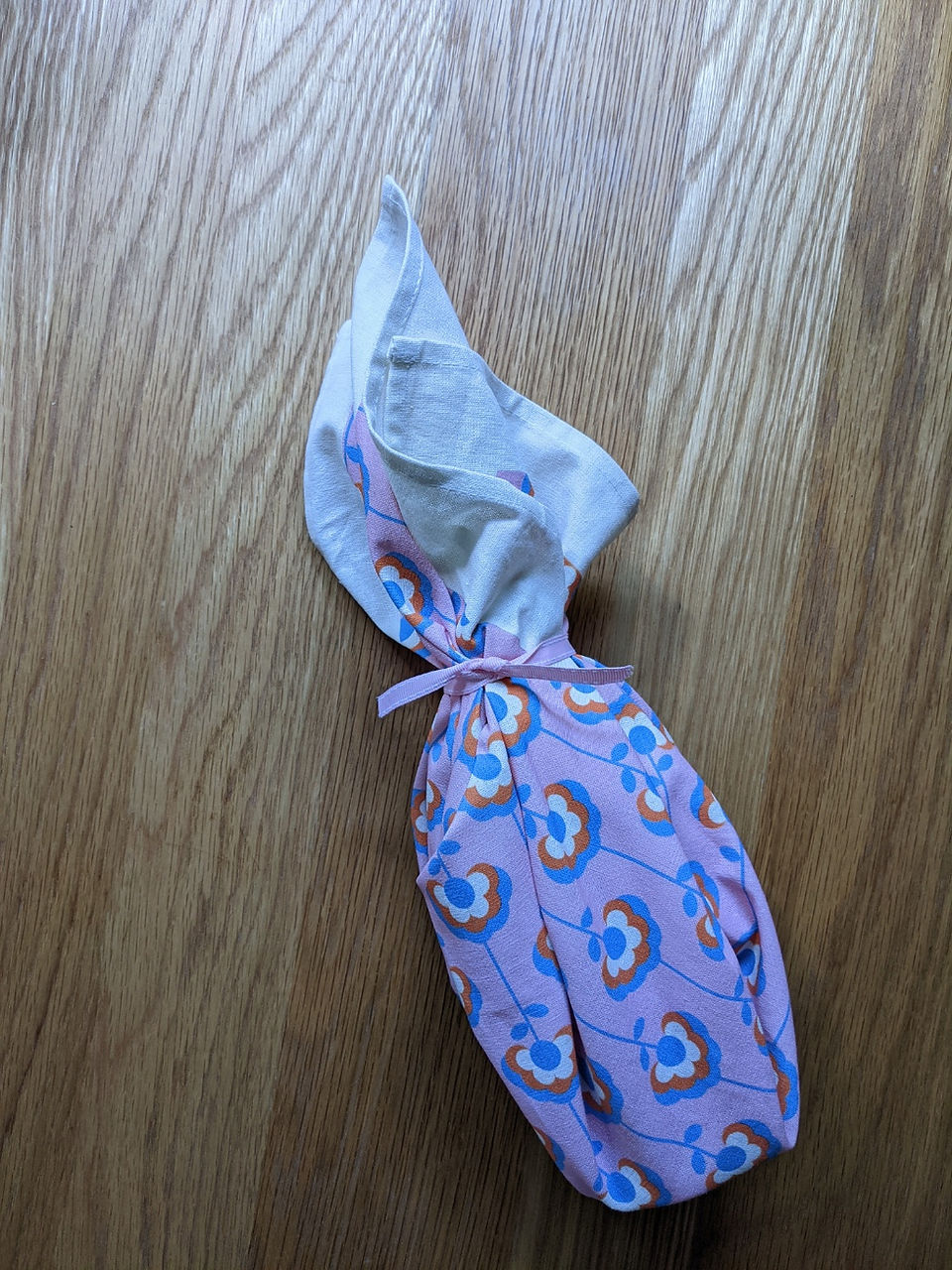 Finished wrapped bottle of wine with pink fabric and flowers