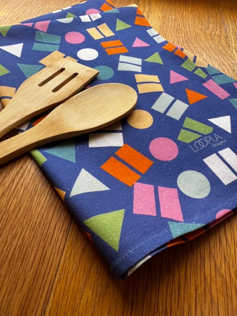 Loopla Confetti Pop pattern tea towel in 100% cotton crepe, styled with a wooden spoon. Hand-designed by a Brisbane surface d