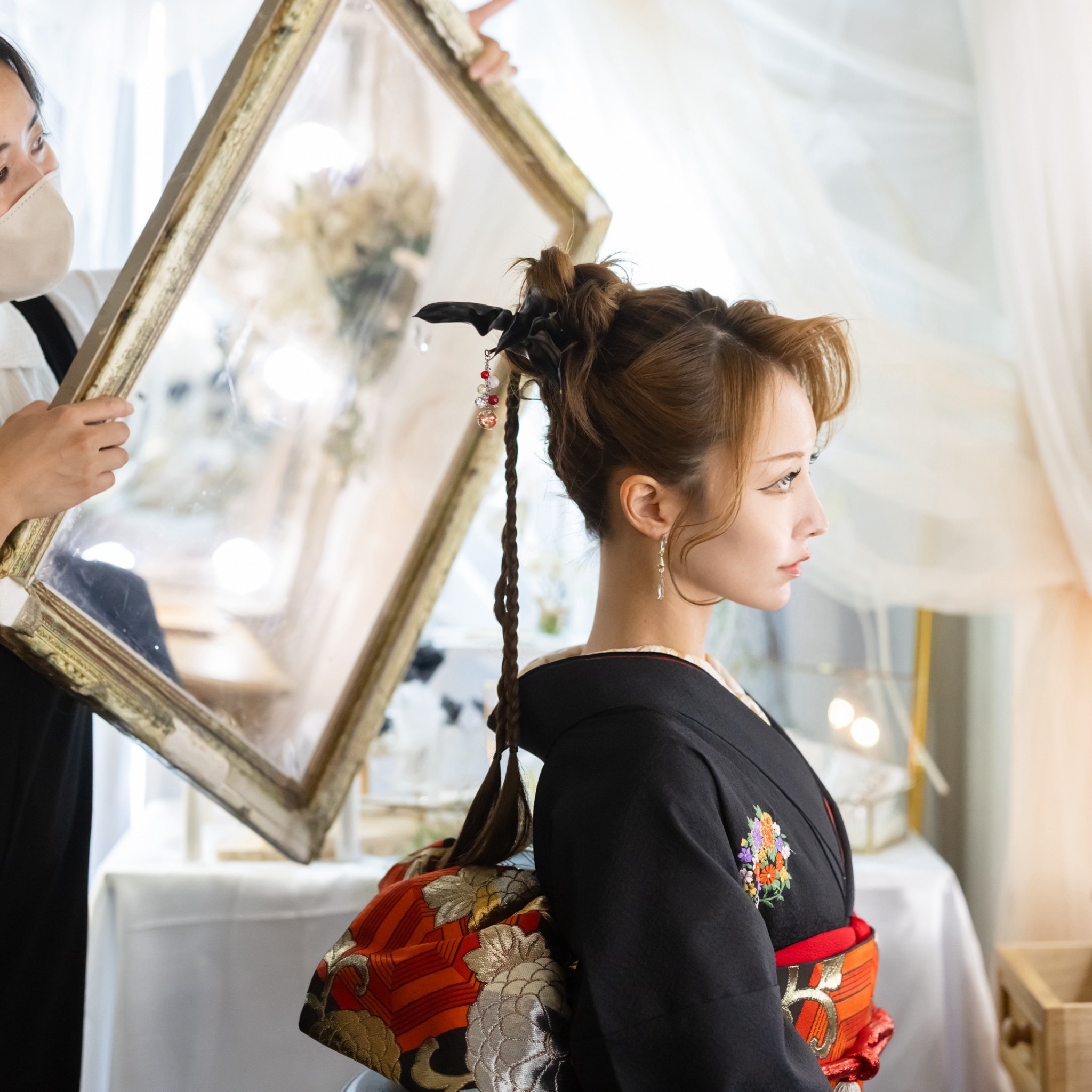 着物姿の女性のヘアセットを鏡で確認する様子