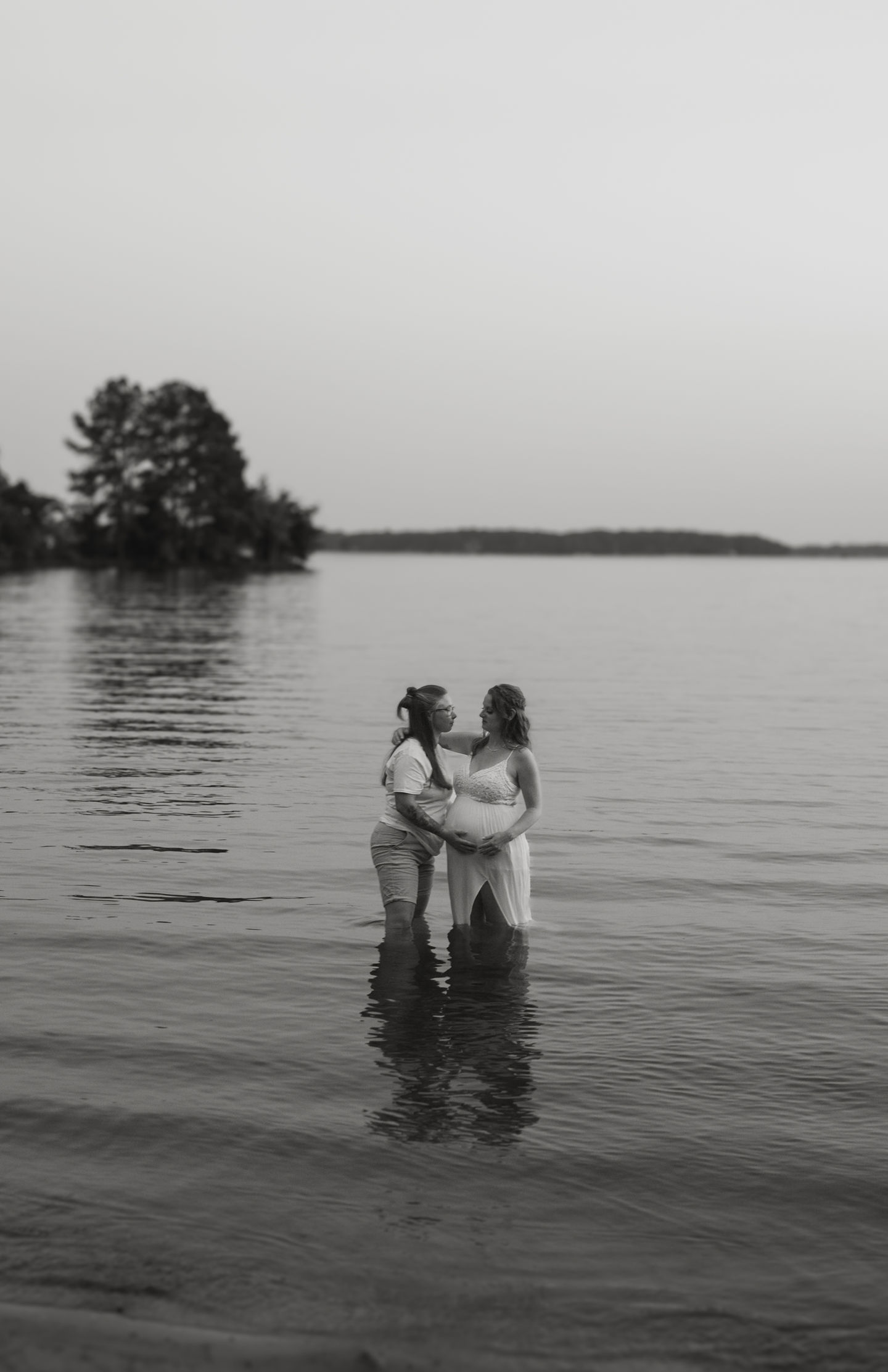 Wide shot of expectant mothers sharing a moment in Lake Norman. 