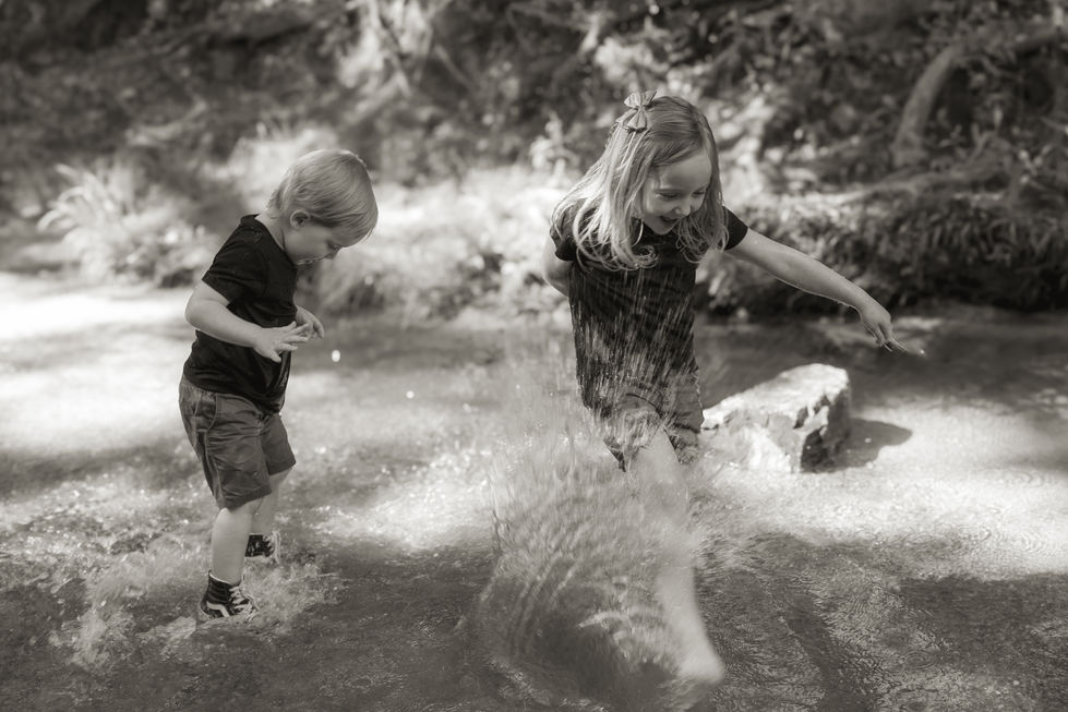 Brother and sister playing at the creek and splashing around. 