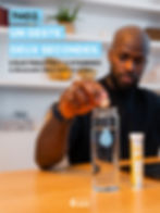 Homme dissolvant un comprimé Hydrapure Nutripure dans une bouteille d’eau, avec le tube d’électrolytes à côté.