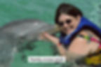Woman in water being kissed by a dolphin