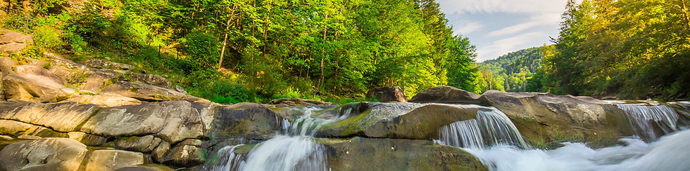 A pristine stream with trees and mountains showing God's creation and our Christian mandate to be good stewards of the earth.