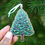 Thumbnail: Wooden Christmas tree decoration featuring an illustration of a Christmas tree covered in coloured baubles. Ornament in hand.
