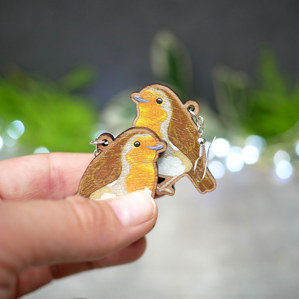 Thumbnail: Christmas robin earrings hung on silver plated hooks, held in front of a festive foliage backdrop