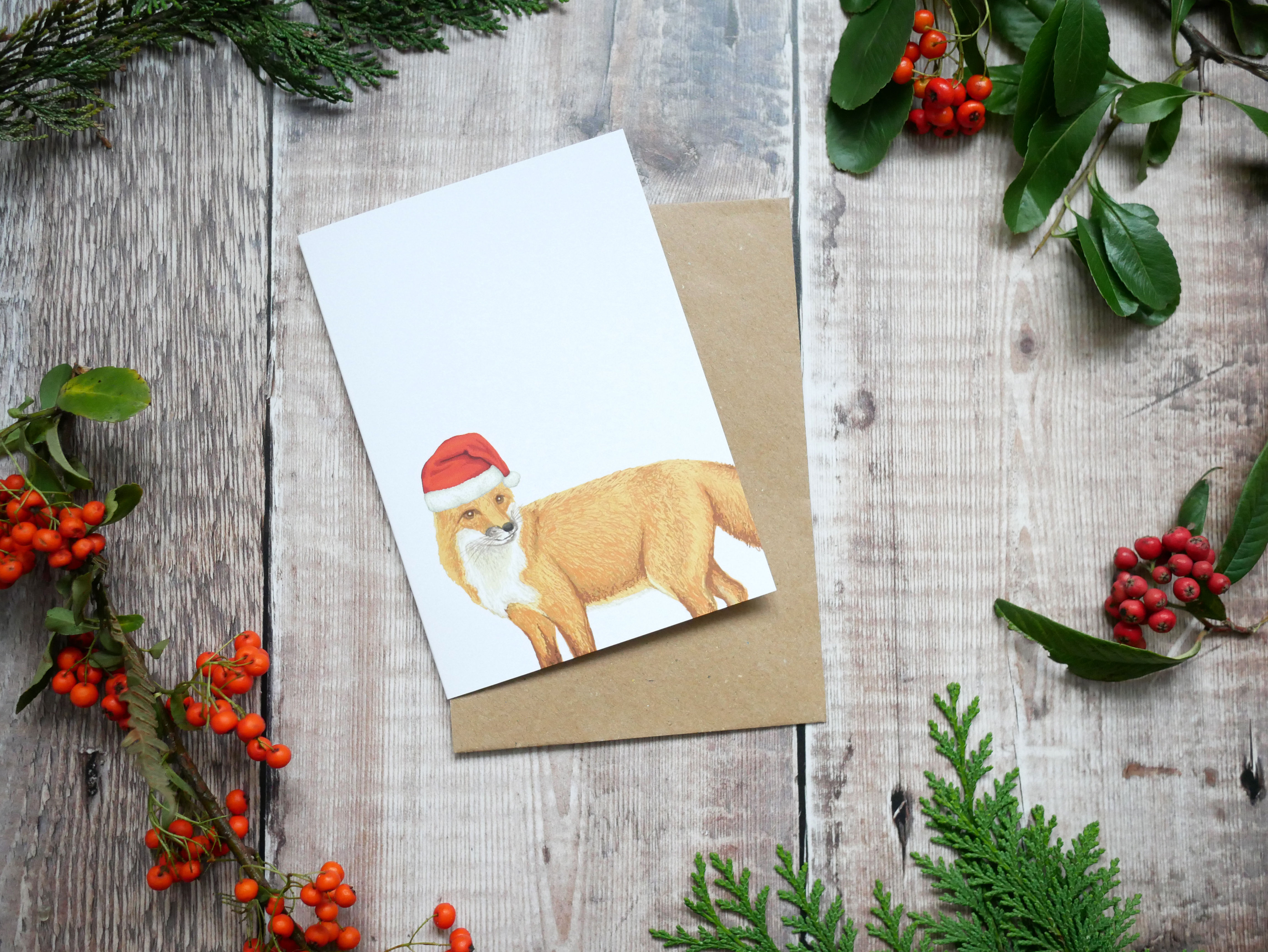 Festive fox wearing a christmas hat on a recycled card with a brown kraft envelope