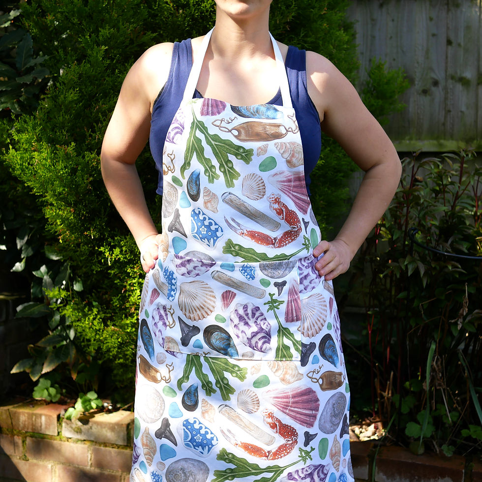 Thumbnail: An organic cotton apron featuring illustrations of beach finds from british beachcombing