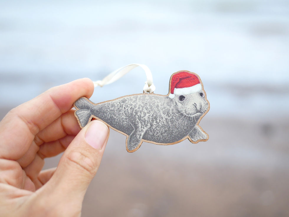 Thumbnail: A wooden Christmas tree decoration of an illustrated seal in a santa hat.