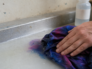 Hand rinsing loose dye out of a hand-dyed fiber reactive tie-dye piece in a sink