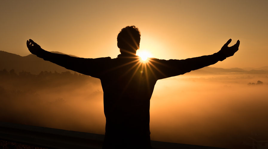 Person with outstretched arms at sunrise