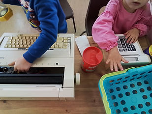 Children using toy tills and role-play equipment to explore early maths and imaginative shop play.