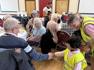 Pre-school child greeting an older adult during an intergenerational visit at a community event.