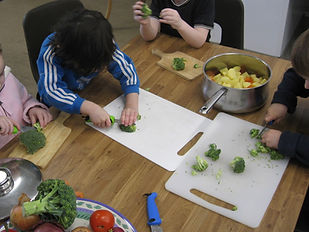 Children chopping vegetables during a supervised cooking and food-preparation activity.