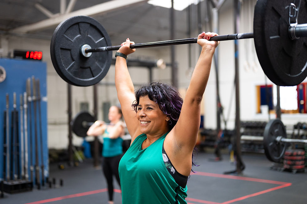 Smiling woman lifting barbell overhead in gym
