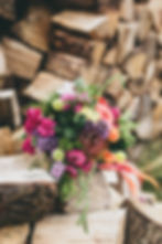Colourful DIY wedding bouquet on a pile of rustic logs