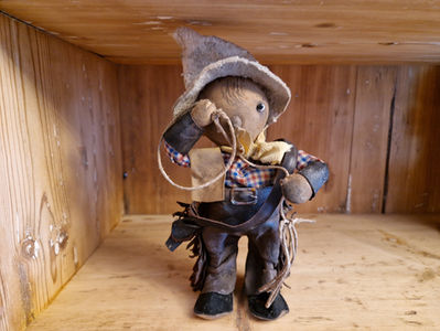 Antiikkilelu, cowboy mekaaninen lelu lasson kanssa sekä nahkahousut että asekotelo