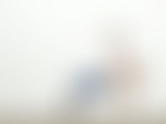 Woman in white top and blue leggings performs a side plank with a kettlebell, against a plain white background, showcasing strength and focus.