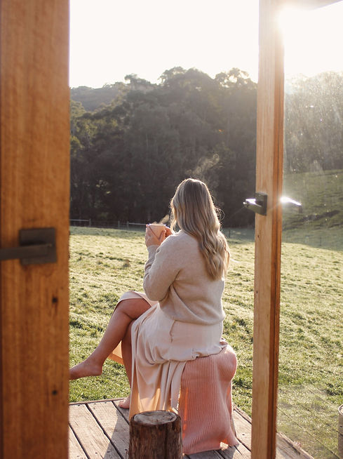 Sharni Ames from Sharni Ames Coaching sitting on a deck overlooking the Yarra Valley in Victoria, Australia