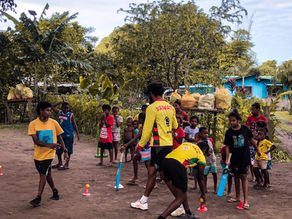 "Children playing cricket with local coaches during a cricket development program."