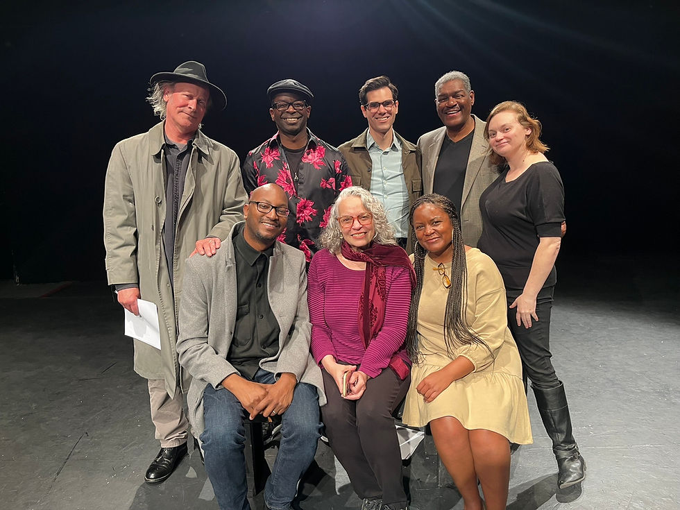 Eight people pose together on a black stage in two rows.