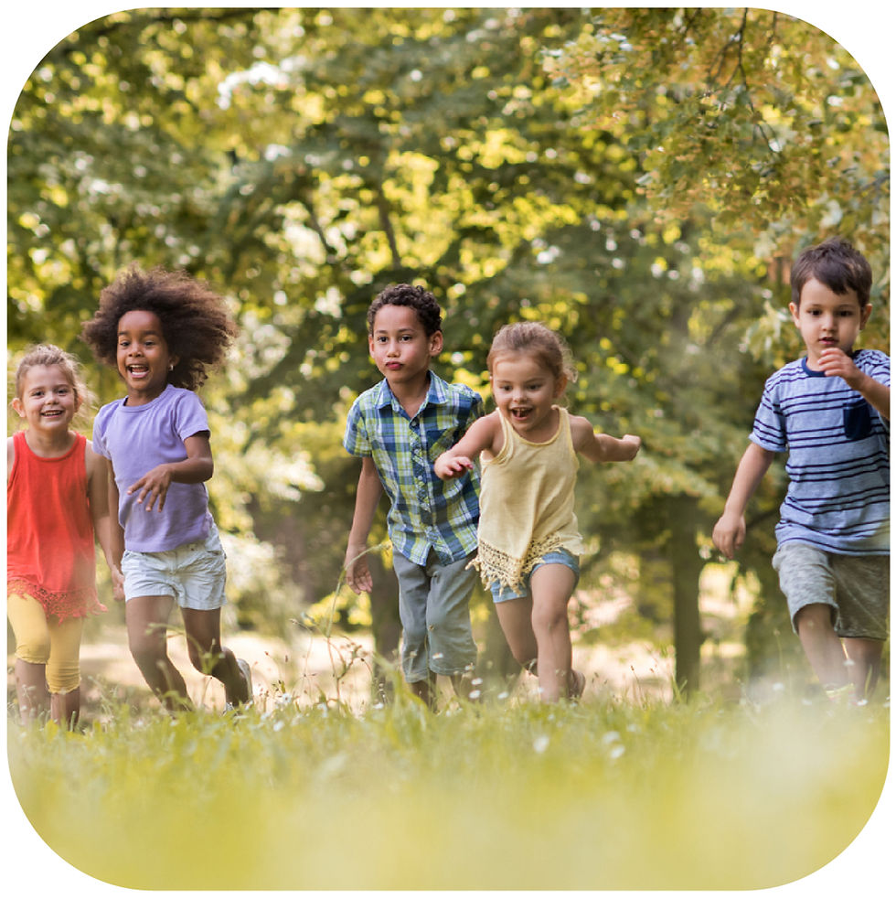 Five children run and smile through a sunny park with green trees and grass, wearing colorful summer clothes.