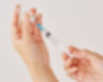 Woman's hand filling syringe with medicine from a vile