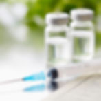 Single use syringe laying on table with medicine viles
