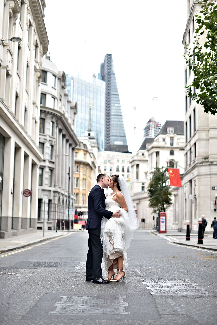 a couple kiss in the middle of the road in london on their wedding day