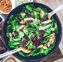 Fresh salad with chicken and pomegranate seeds in a black bowl, meal planning guidance.