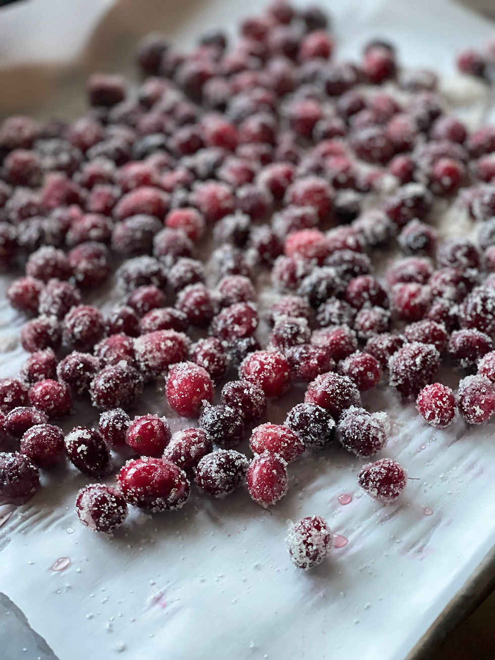 Ruby-red sugared cranberries on a cooling rack, coated in sparkling sugar, ready to garnish desserts or cocktails for holiday entertaining.