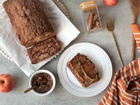 A sliced loaf of cardamom apple cinnamon bread with a buttery cinnamon crumble topping and small pieces of apple baked into the bread.