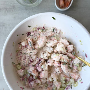 Buttery garlic prawn salad served in toasted rolls with lemon, chives, celery, and fresh herbs.