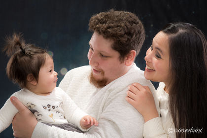 New parents gazing lovingly at their baby daughter during a softly lit studio session.