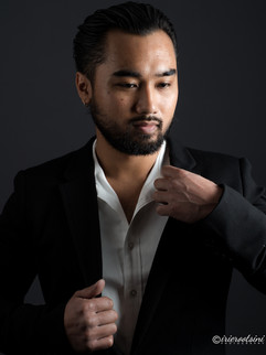 Confident headshot pose adjusting suit collar in a black jacket