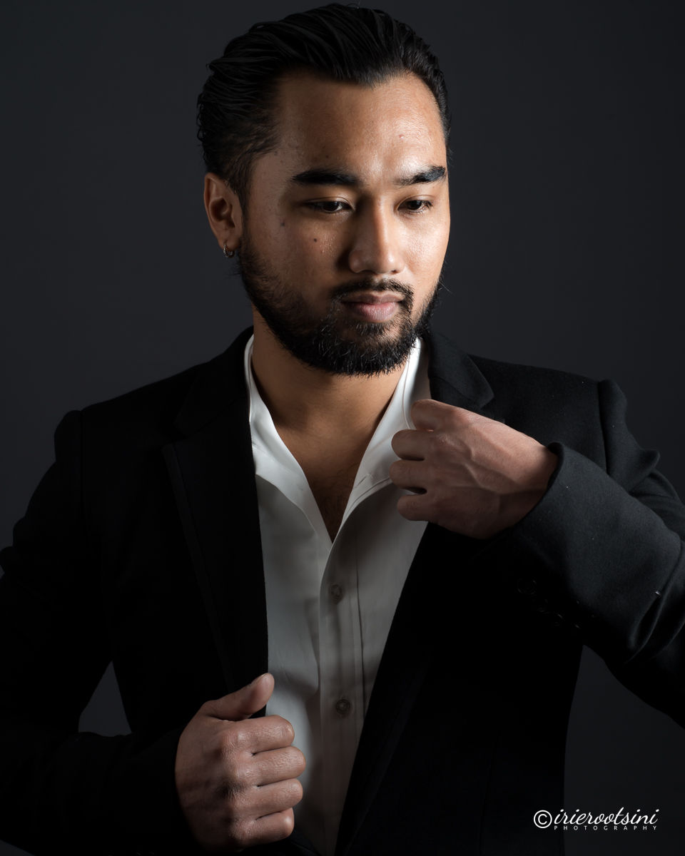 Confident headshot pose adjusting suit collar in a black jacket