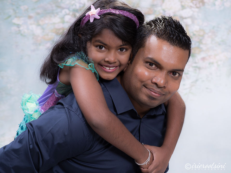 Daughter piggybacking on her father’s back, both smiling for a playful studio photo.