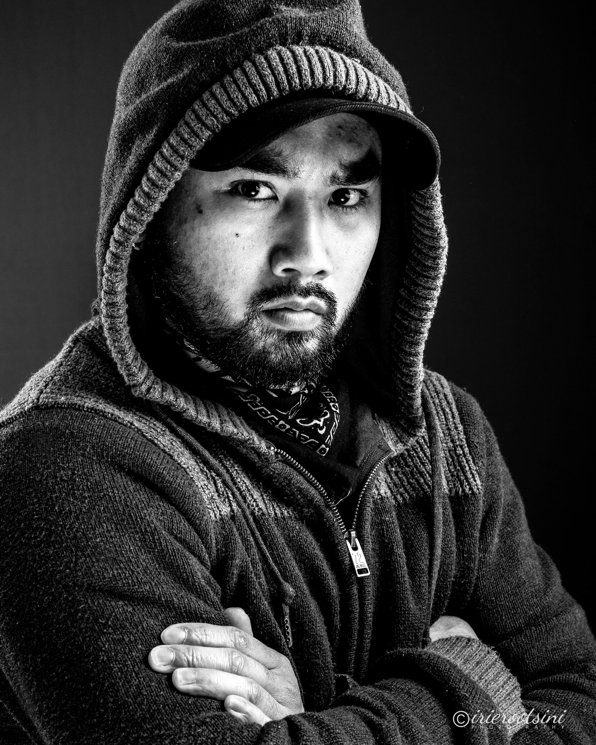 Black and white studio portrait of male actor in hoodie, dramatic side lighting for intensity.