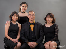 Parents with two teen daughters in elegant black, smiling together during a studio session.
