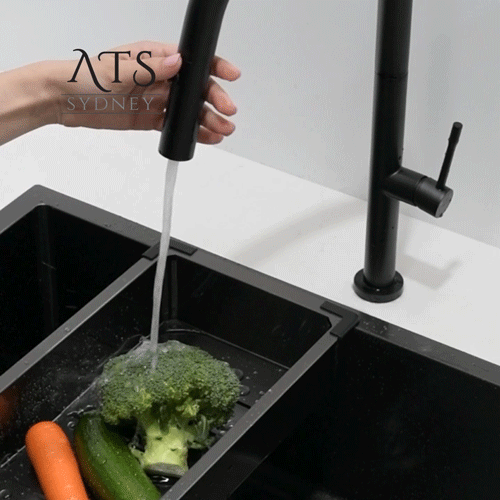 Promotional video shows a black kitchen faucet with a veggie spray being used on vegetables in a colander tray.