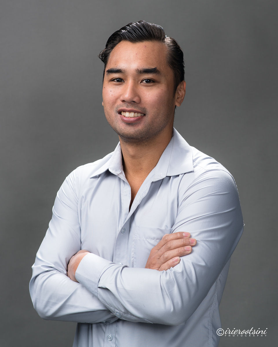 Clean-cut actor headshot with arms crossed in light shirt, smiling