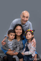 Parents with their son and daughter, captured in a warm studio portrait on grey background.