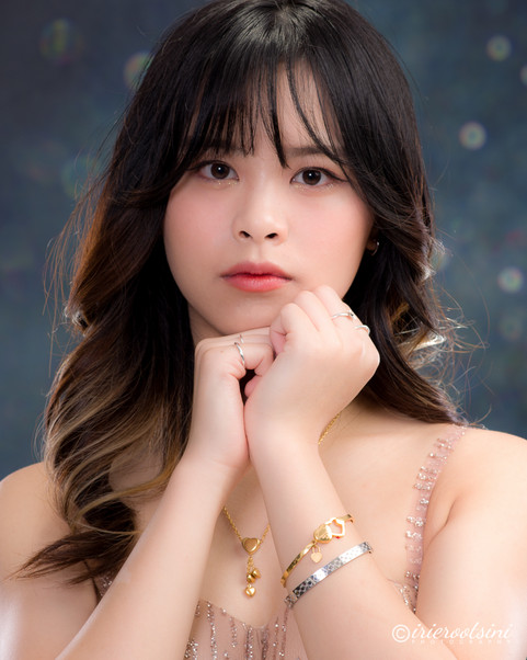 A young woman with long black hair and gold jewellery presents a captivating look in her modelling headshot.