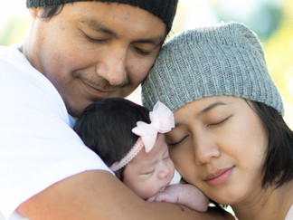 Parents holding their baby close with eyes closed during an outdoor newborn portrait in Sydney.