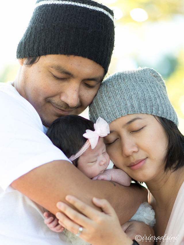 Parents holding their baby close with eyes closed during an outdoor newborn portrait in Sydney.